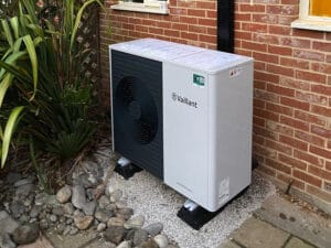 Outdoor air source heat pump beside brick wall
