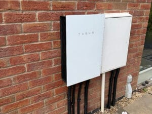 Tesla battery unit mounted on an exterior brick wall
