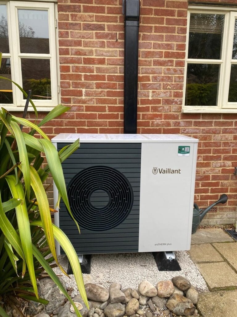 Outdoor heat pump unit beside brick wall.