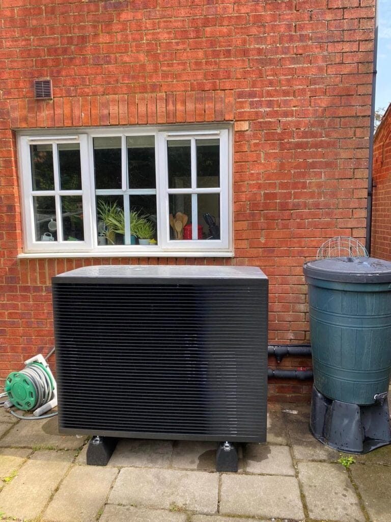 Outdoor heat pump unit beside brick house window.