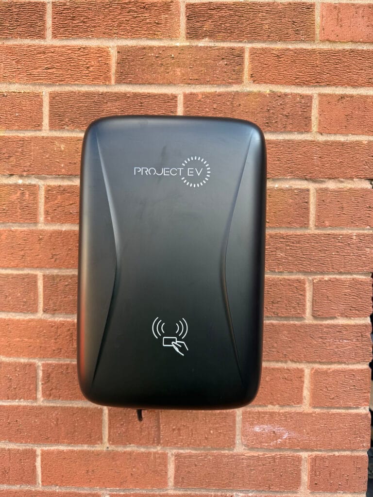 Project EV electric vehicle charging station on brick wall.