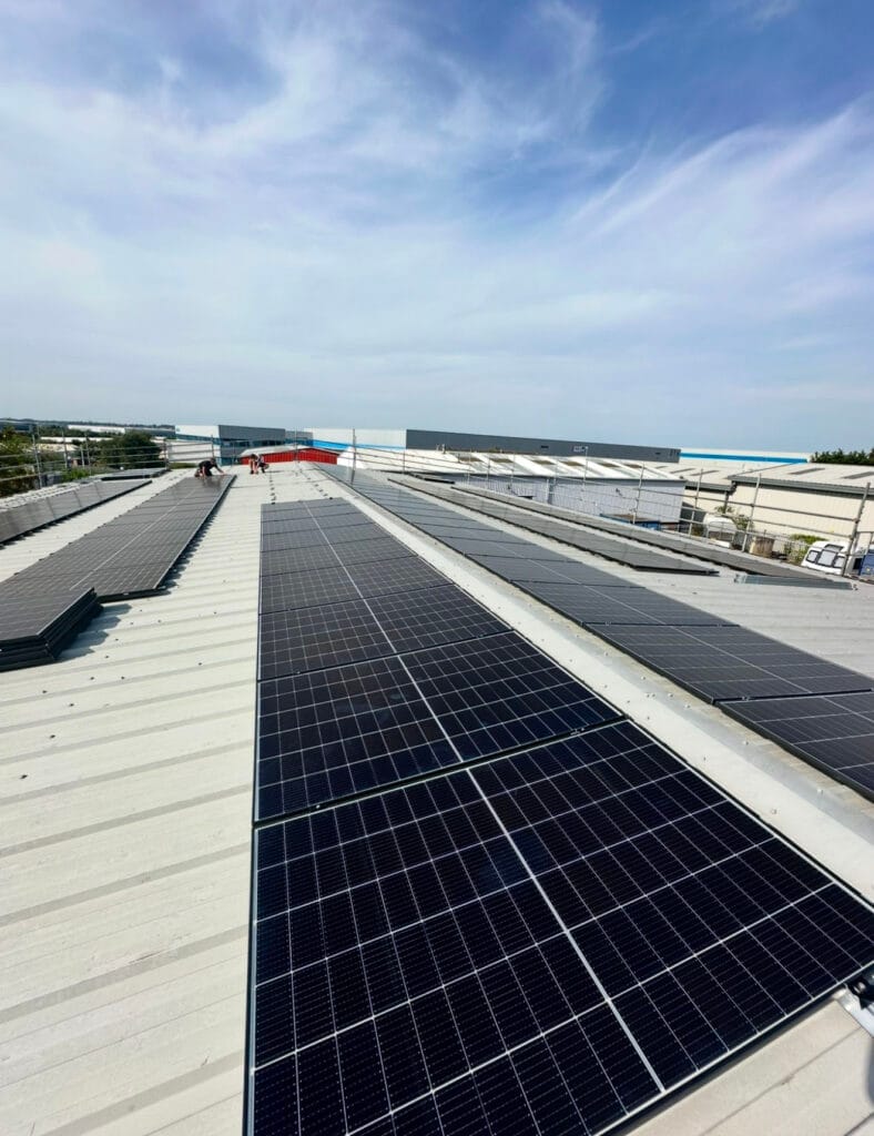Solar panels on industrial rooftop under blue sky.