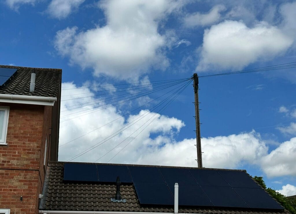 Rooftop solar panels under cloudy sky.
