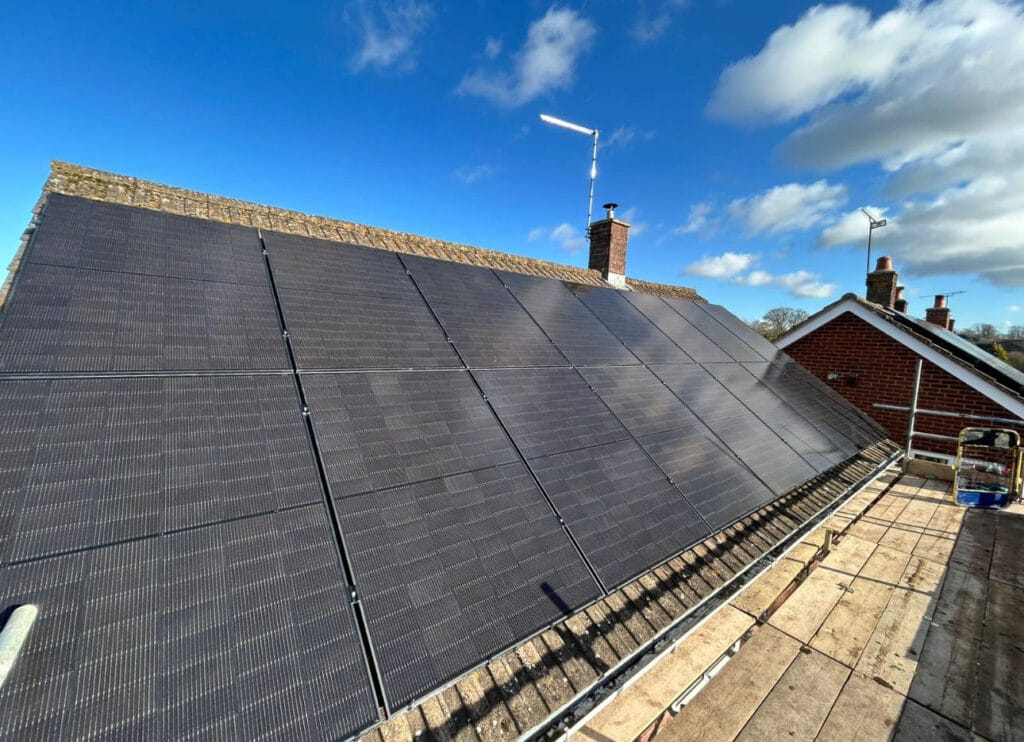 Solar panels on house roof under blue sky.