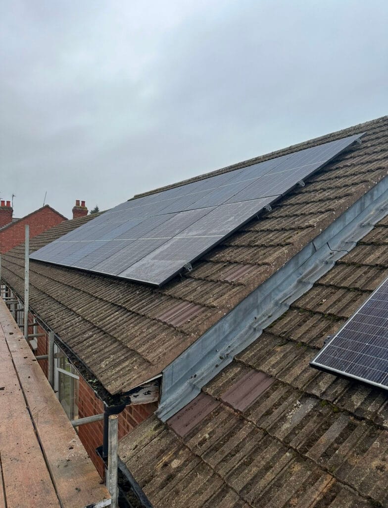 Solar panels installed on sloped roof, cloudy sky background.