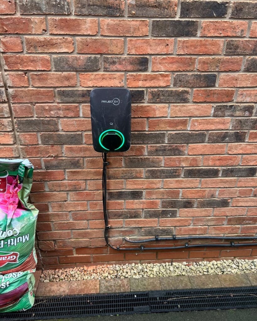 Electric vehicle charger on brick wall.