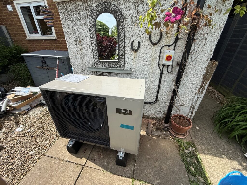 Outdoor air conditioning unit near garden wall.