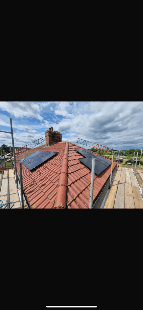 Red roof with solar panels and scaffolding.