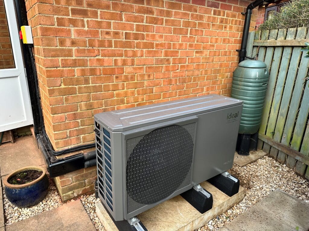 Outdoor heat pump next to brick wall.